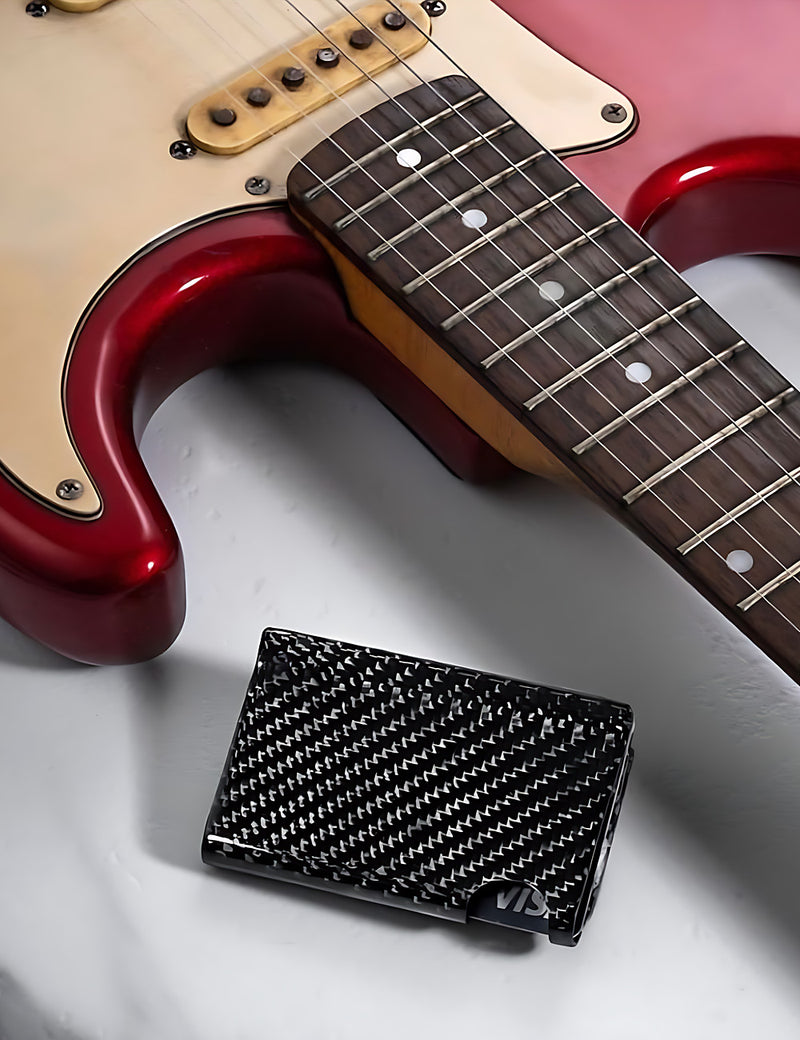 Carboluxe carbon fiber wallet next to a guitar
